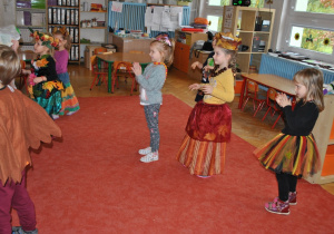 Dzieci stoją rozproszone na dywanie i tańczą taniec "kaczuszki". Ujęcie 2